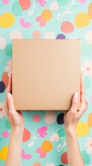 Hands holding blank brown gift box, giving a present or delivering a package, with colorful abstract floral pattern background, space for copy