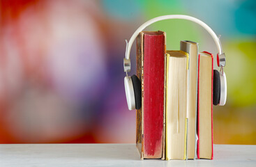 audiobooks for the springtime  with  stack of books,headphones and colorful blurry backgrounds