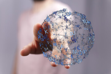 A person holds a digital globe made of interconnected lines and letters, symbolizing technology and connection
