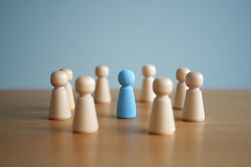 Wooden figures with one blue figure standing out among others on a wooden surface light wood standing figures