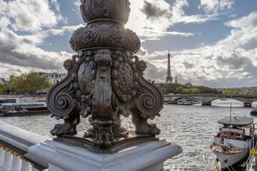 Fototapeta premium The sun illuminates the detail of a street lamp on the Alexandre III bridge in Paris, France, with the Eiffel Tower in the background