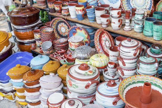 Colorfully painted clay pots, Gyuvech , displayed neatly on a shelf. Craftsmanship and traditional design in focus.