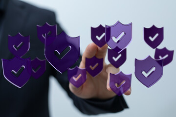 Concept of cybersecurity, data protection, and online safety. Hand interacting with floating shield icons with check marks, symbolizi