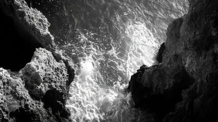 A black and white photo of crashing waves against a rocky cliffside.