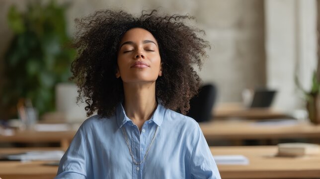 Content Black businesswoman meditating in yoga pose at work practicing breathing for stress relief