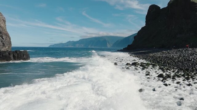Aerial drone footage flying low over the Atlantic Ocean along the rugged cliffs of Miradouro Ilh&eacute;us da Ribeira da Janela on Madeira&rsquo;s northern coast. Powerful waves crash against the rocky shoreline