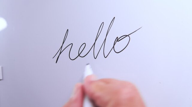 Person's hand writing the word hello in cursive on a whiteboard, isolated on a white background