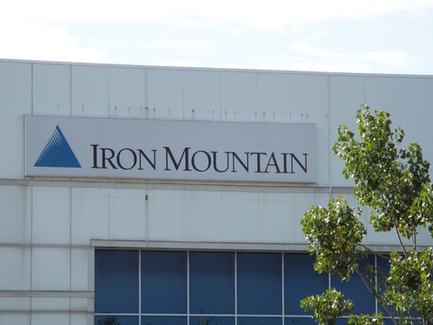 Gloucester, ON, Canada-July 4,2025:The "Iron Mountain" corporate sign features a blue triangle logo on a white building exterior on Cyrville Rd.
