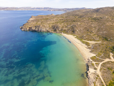 Aerial view of turquoise waters meet the rugged coastline, creating a stunning contrast along the shores of Rivari Lagoon, Rivari Lagoon, Milos, Greece.