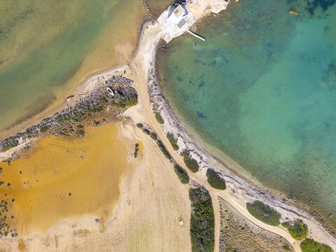 Aerial view of the contrasting turquoise waters meeting the golden sands at Rivari Lagoon, a captivating coastal scene, Rivari Lagoon, Milos, Greece.