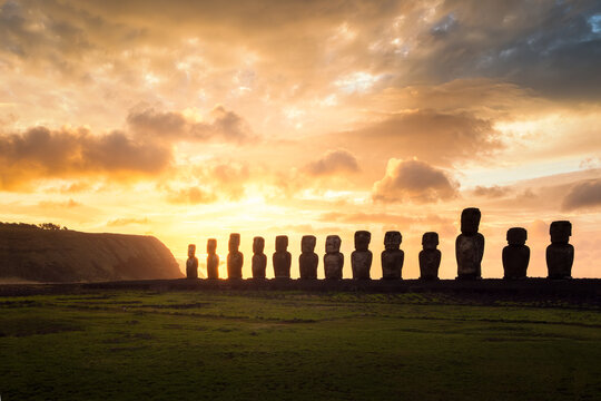 Sunrise at Ahu Tongariki, Rapa Nui (Easter Island), Chile, with silhouettes of colossal moai statues against orange sky. Tongariki is the largest ahu in Rapa Nui and counts 15 moai statues.