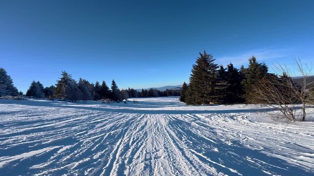 Beautiful POV ski landscape on the mountains. Skier skis down a snowy mountain trail in sunny weather.