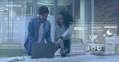 Pointing woman in light sweater leaning over laptop at office meeting area, with data overlays