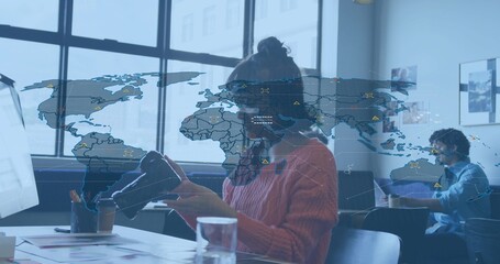 Holding and inspecting VR headset, Asian woman wearing rust sweater and glasses at coworking table