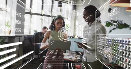 Collaborating business-casual team pointing at tablet and holding laptop in office with AR graphics