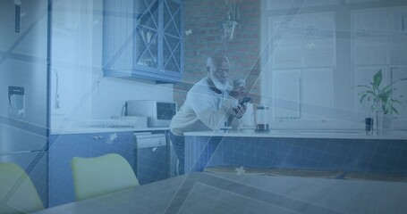 Leaning man wearing light sweater holding mug and smartphone on kitchen island, French press nearby