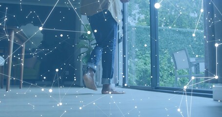 Stepping barefoot man wearing rolled dark blue jeans on light floor near glass doors, data overlay