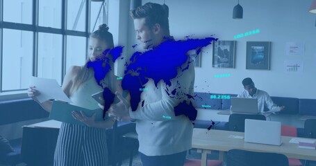 Reviewing documents, coworkers wearing sweater and striped skirt at office with laptop and blue map