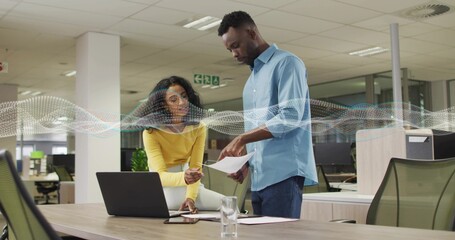 Collaborating yellow-top woman and blue-shirt man reviewing laptop pages at office waveform