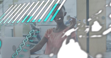 Smiling woman in pink blouse holding pen pointing at laptop at desk, showing holographic chart