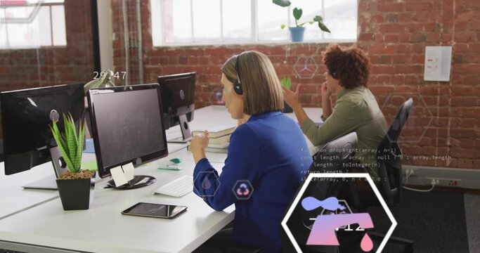 Typing woman in blue blazer and overear headset at open-plan office, with keyboard and hexagon UI - Powered by Adobe