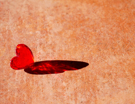 a red heart casting a red shadow on the floor