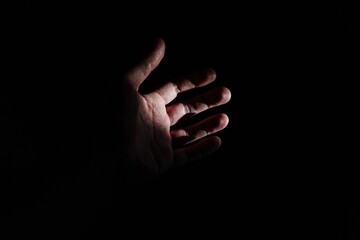 A reaching hand in darkness symbolizing hope rescue help support assistance isolation vulnerability protection