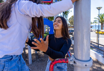Young woman assisting a child on playground, sharing a happy moment outdoors