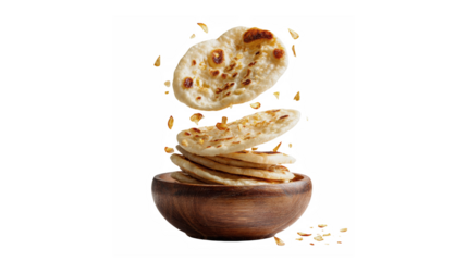 A dynamic presentation of warm naan bread pieces floating above a wooden bowl against a black background.