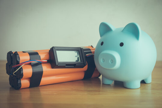 Piggy and with time bomb on wooden table. Concept of personal financial problem, high inflation, recession crisis, risk and savings management, loss investment, expenses overburden, installment.