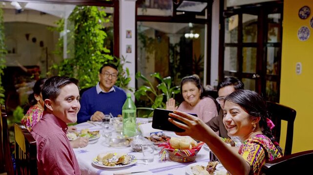 Young woman takes a self-portrait of her family during a family celebration.