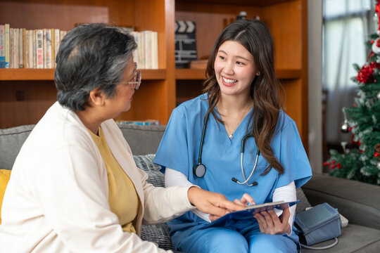 Nursing home, Asian woman or doctor with clipboard writing medical problem of elderly woman patient. Healthcare, tech and nurse caregiver help consulting with senior retirement in living room at home.