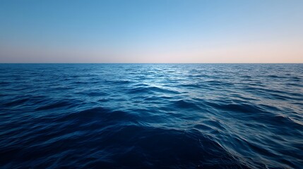 Obraz premium A calm deep blue ocean stretches to the horizon under a clear soft sky evoking a sense of peace and solitude
