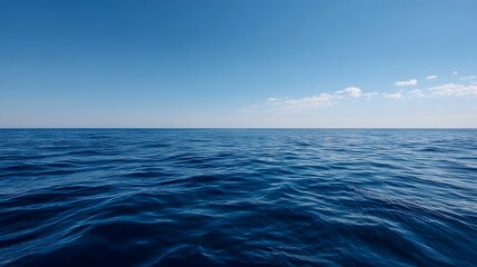 Obraz premium A vast deep blue ocean meets the clear sky at the horizon with gentle waves reflecting sunlight