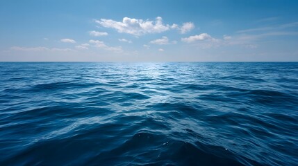 Fototapeta premium Vast blue ocean stretching to the horizon under a clear sky with scattered clouds
