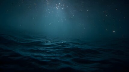Ethereal light rays pierce the dark blue ocean surface illuminating sparkling particles