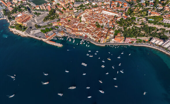 Aerial view of the dramatic coastline where the terracotta rooftops of the city meet the azure sea dotted with sailboats, Marseille, Provence-Alpes-Cote d'Azur, France.