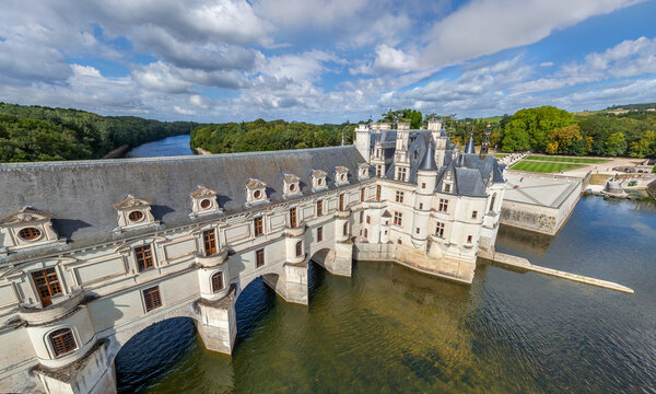 Aerial view of the Chateau de Chaumont gracefully spanning the Loire River, its white stone contrasting with the deep blue water and lush green banks, Chaumont-sur-Loire, Centre-Val de Loire, France.