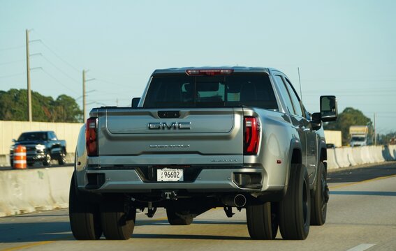 Sarasota, Florida, U.S - Jan 3, 2026 - A silver GMC Sierra Denali dually pickup truck drives along a highway under a clear, bright morning sky
