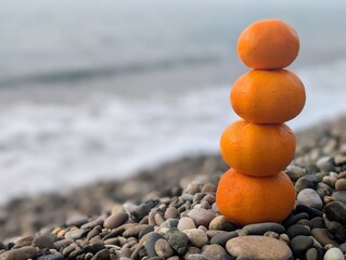 A close-up of a tower of ripe orange tangerines on the seashore.