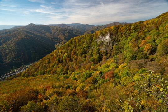 Aerial view of autumn's fiery hues painting the rolling hills and deep forests, with a dramatic cliff face punctuating the landscape, Baranovo, Banska Bystrica, Slovakia.