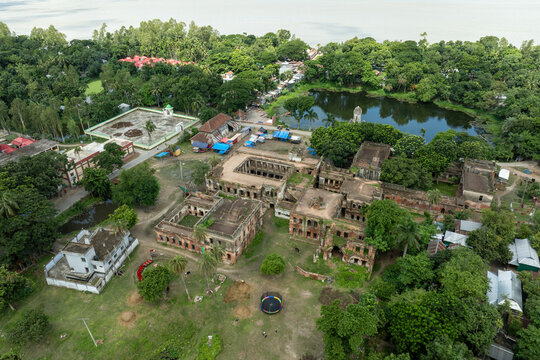 Aerial view of crumbling Zamindar Bari stands amidst verdant trees and a serene pond, its faded grandeur reflecting in the still water, Manikganj, Dhaka Division, Bangladesh.