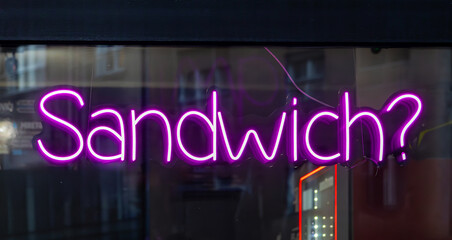 Sandwich neon led glowing commercial sign outside on building facade