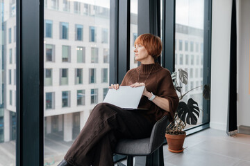 White woman aged 49 working on laptop in modern coworking space