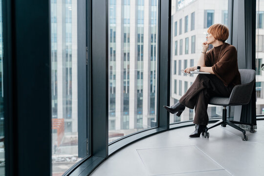 Modern professional mature red hair woman with thoughtful expression sitting