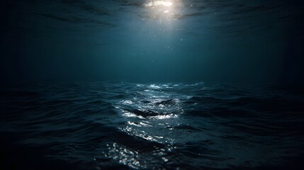 Sunlight beams penetrate the deep blue ocean surface from an underwater perspective creating a tranquil ethereal mood