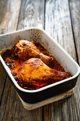Baked chicken drumsticks in baking dish on wooden table