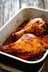 Baked chicken drumsticks in baking dish on wooden table