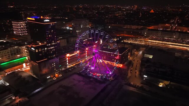 Aerial night video showing Munich East skyline. Umadum Ferris Wheel dominates Werksviertel-Mitte near Ostbahnhof during December 31 celebrations. Naechtliches Luftbild von Werksviertel Muenchen.