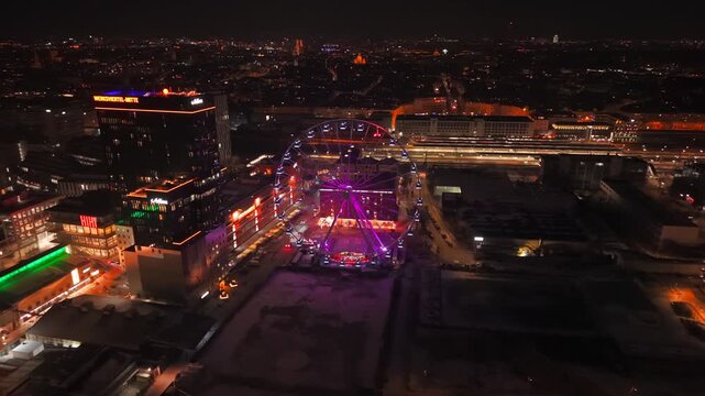 Luftaufnahme per Drohne von Werksviertel-Mitte in Muenchen bei Nacht. Beleuchtetes Umadum Riesenrad nahe Muenchner Ostbahnhof an Silvester. Drone night footage of Werksviertel Munich with Umadum